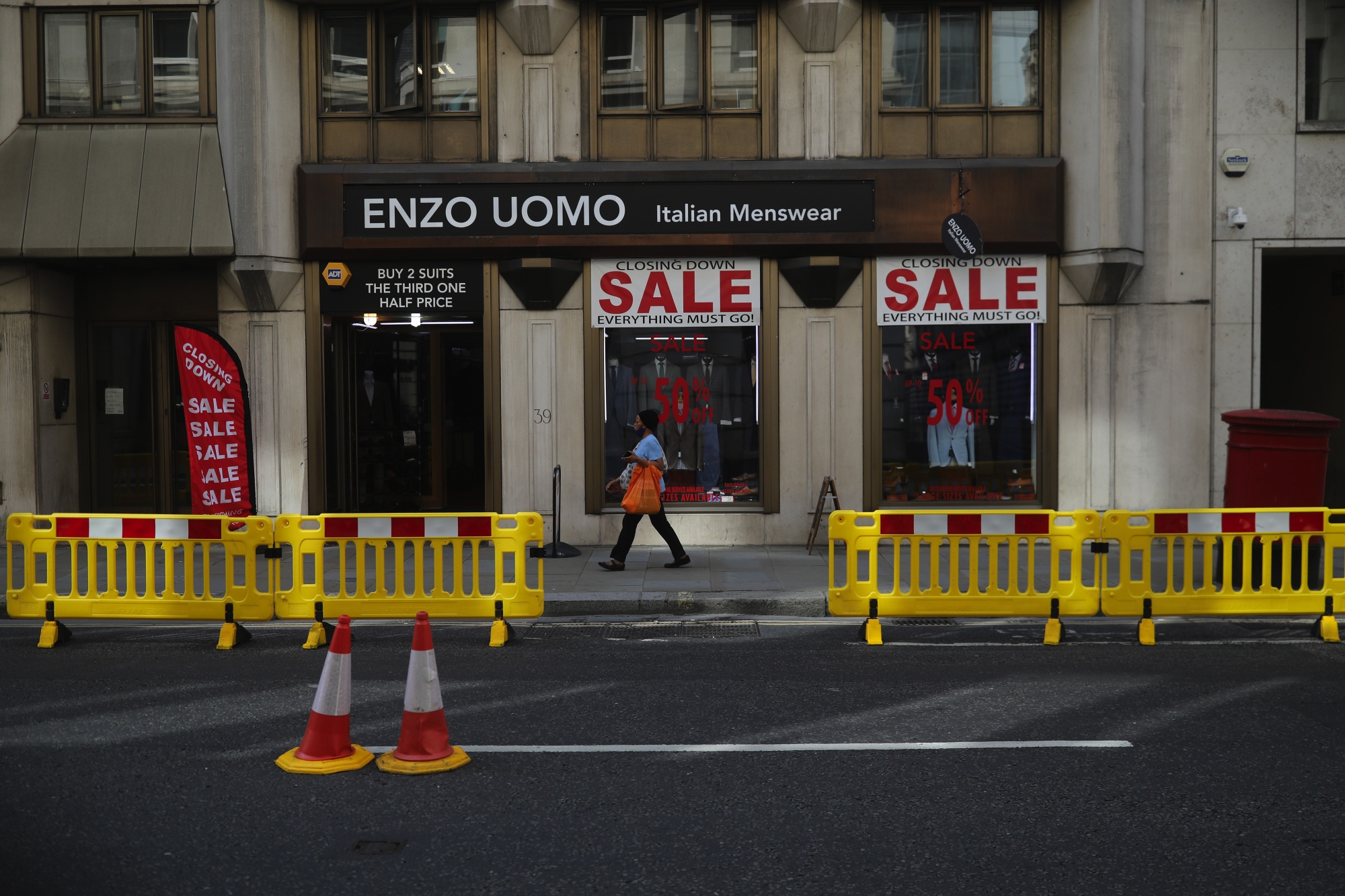 A pedestrian passes a suit store offering closing down sale prices in London on Aug. 12.