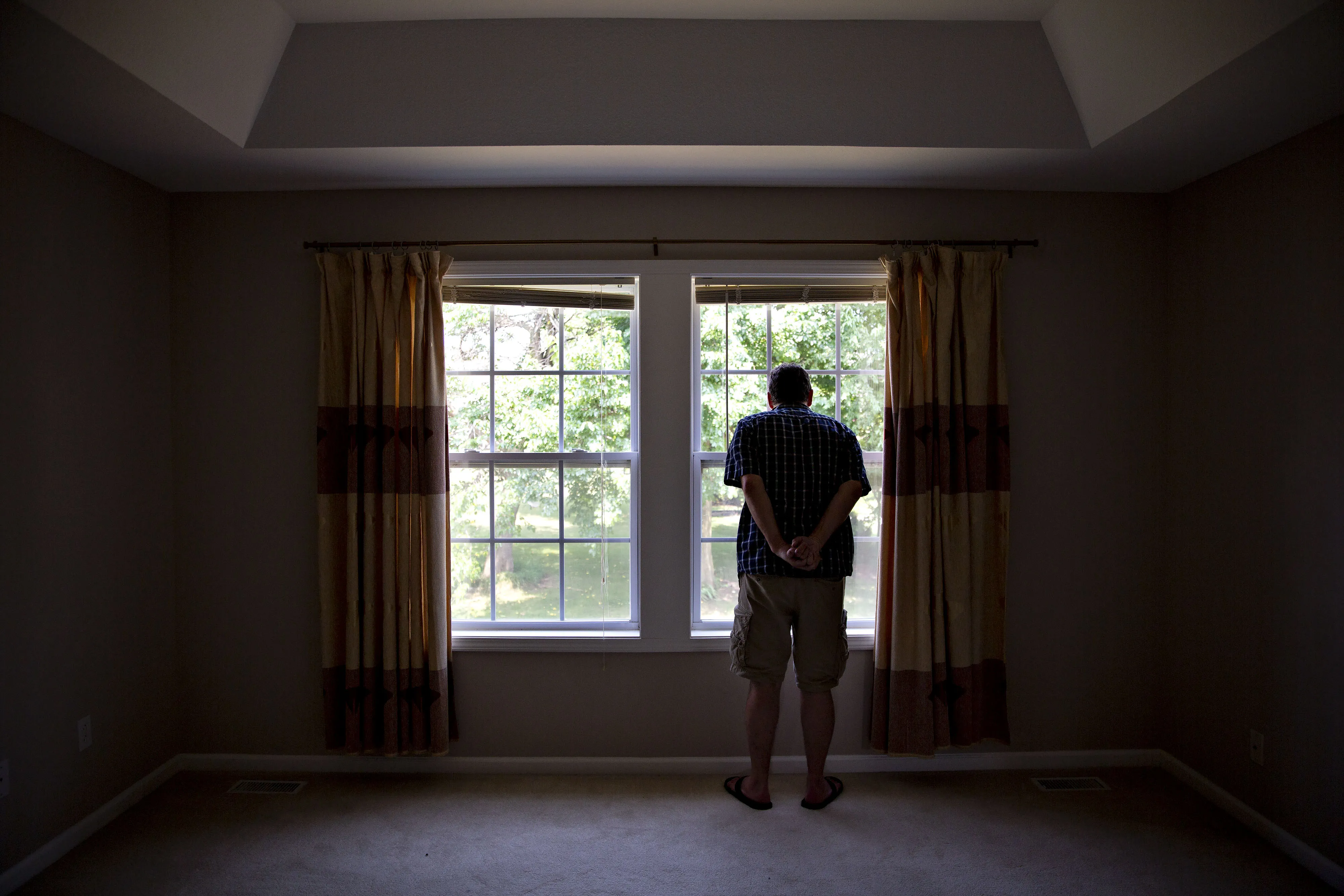 A prospective home buyer looks out the master bedroom window at a house for sale.