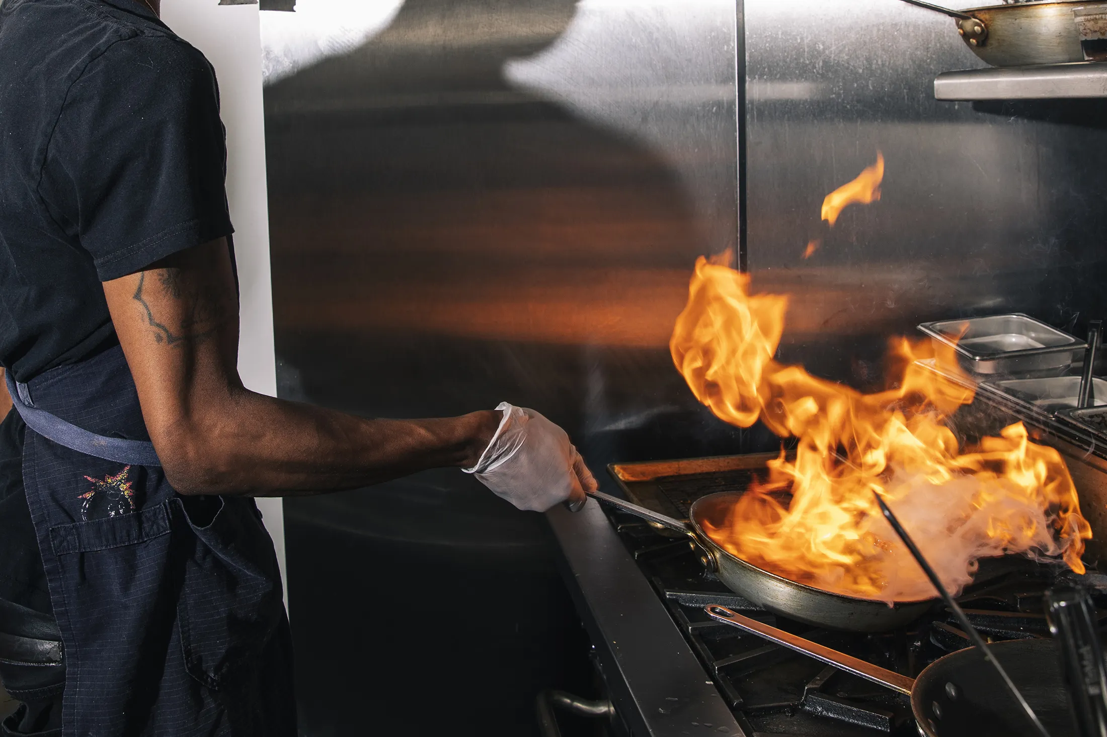 A chef cooks over a flame at a restaurant in the Oakland Food Hall in 2021.