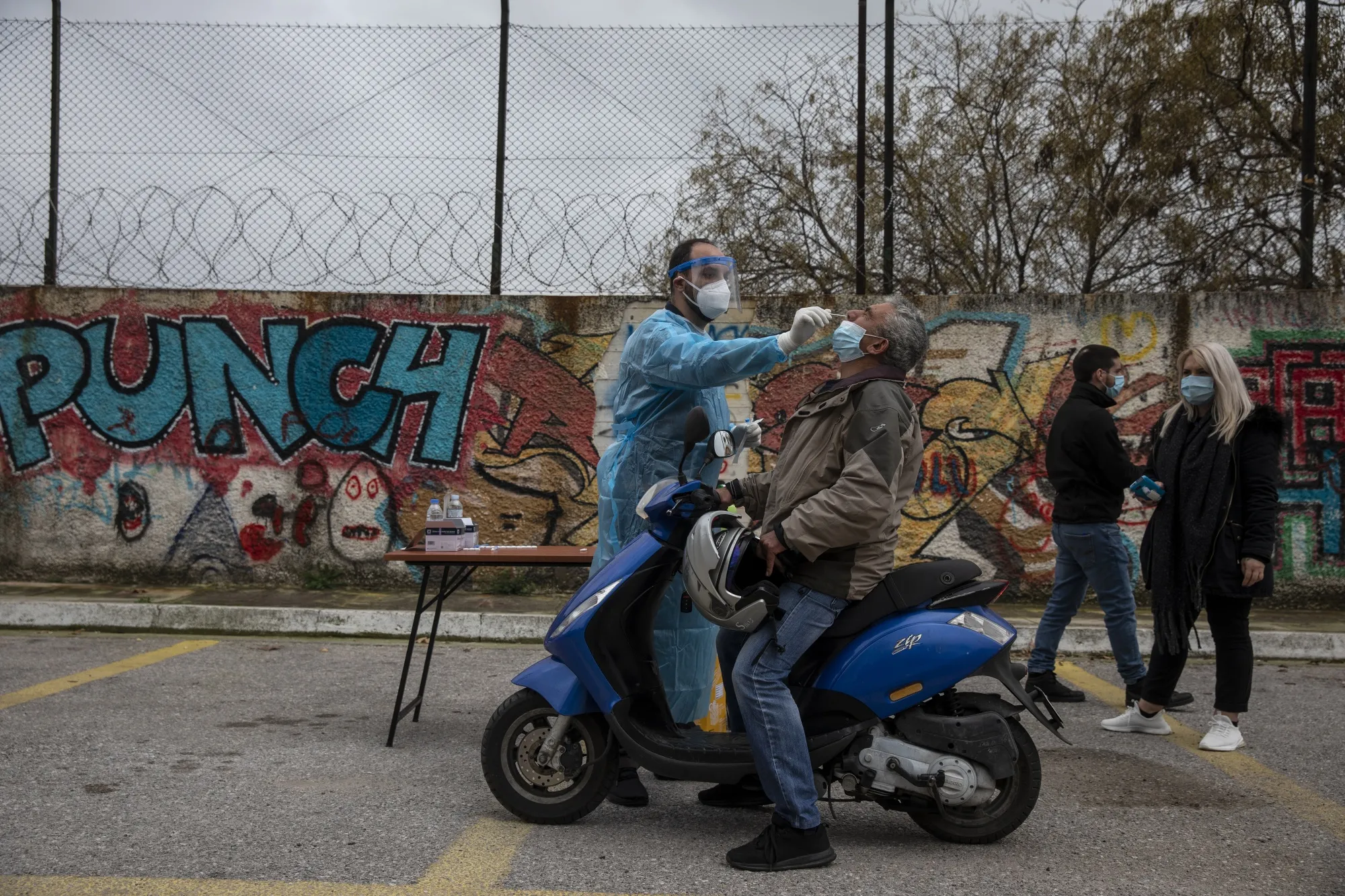 A medical worker takes a sample from a man on a scooter at a Covid-19 drive-through testing station, at Menidi suburb, near Athens, Greece.