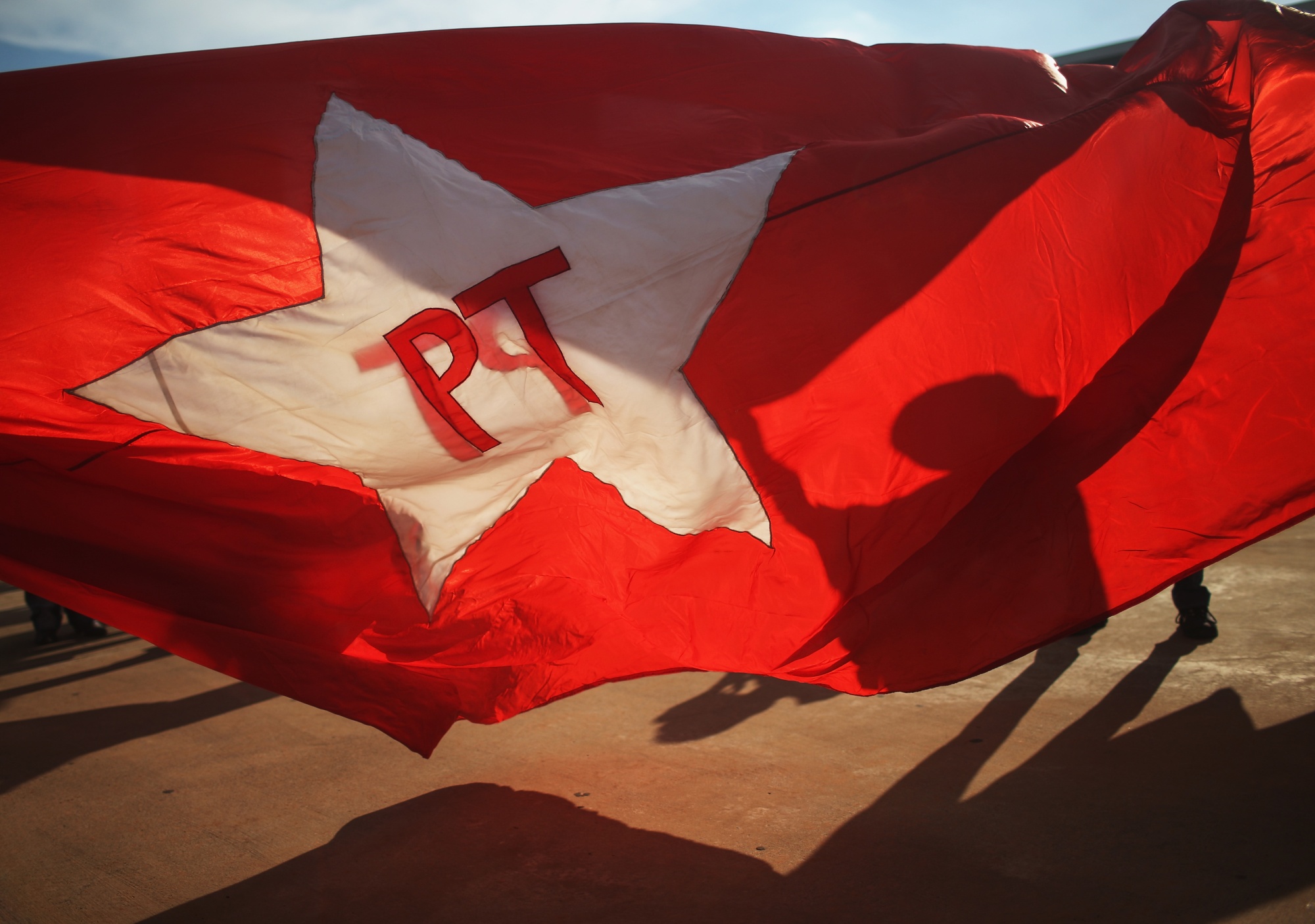 BRASILIA, BRAZIL - MARCH 18: A supporter of President Dilma Rousseff and former President Luiz Inacio Lula da Silva carries a Worker's Party (PT) flag to a demonstration at Esplanada dos Ministerios in March 18, 2016 in Brasilia, Brazil. A Brazilian justice suspended the cabinet appointment of 'Lula' who now cannot begin work as chief of staff for current President Dilma Rousseff. (Photo by Mario Tama/Getty Images)