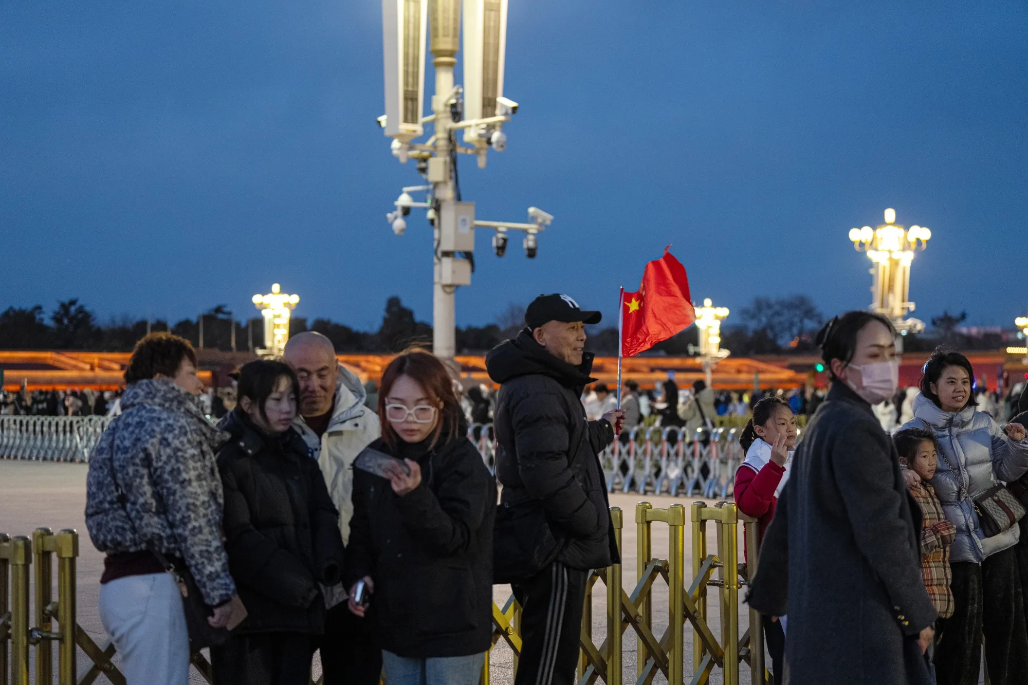 A visitor holds a Chinese flag during a flag lowering ceremony at Tiananmen Square in Beijing.