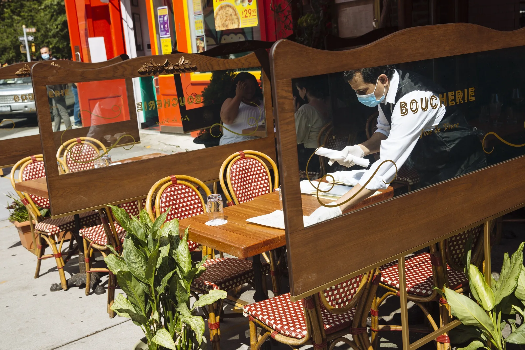 A worker wearing a protective mask and gloves sets a table outside a restaurant in the West Village neighborhood of New York on June 24, 2020.&nbsp;