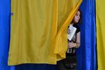 A woman walks out of a voting booth at a polling station during Ukraine’s parliamentary election in Kiev on July 21.