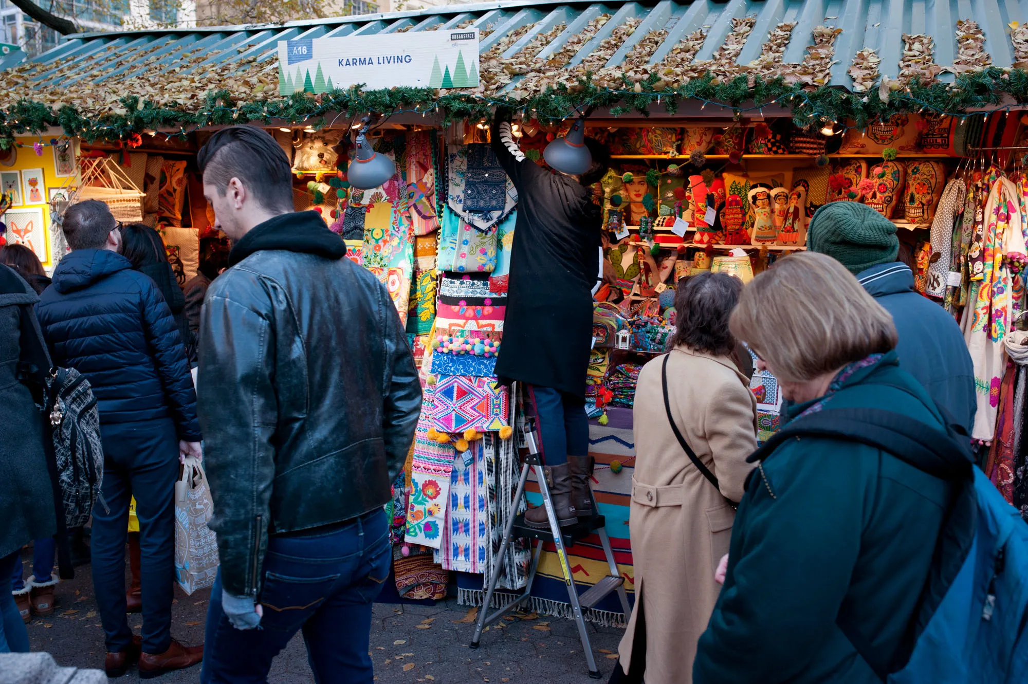 Shoppers pass in front of the Karma Living kiosk at the Union Square Holiday Market in New York, U.S., on Friday, Dec. 1, 2017.&nbsp;
