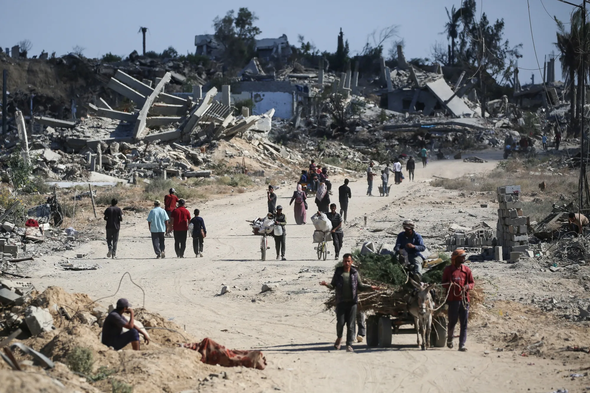 Displaced Palestinians pass destroyed buildings as they return to their homes in the in al-Zahra area,&nbsp;in the Gaza Strip, on Oct. 14.