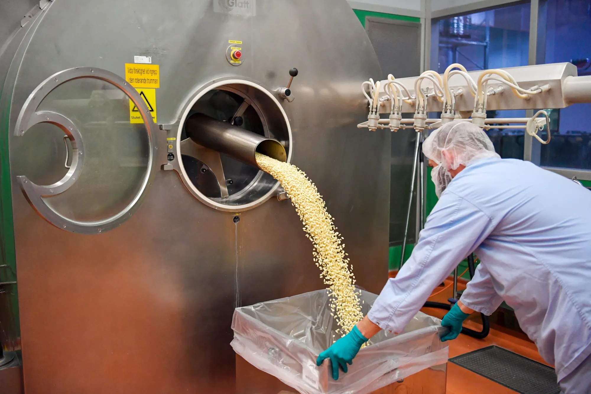 Newly coated tablets flow into to a container at AstraZeneca Plc's new Biologics factory in Sodertalje, Sweden.