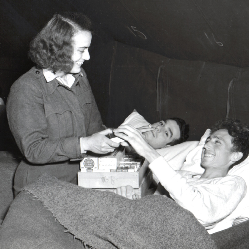 An American Red Cross worker gives cigarette rations to a former US, prisoner-of-war soldier at a field hospital in Germany.
