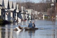 Two men paddle in a row boat on a street