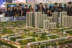 Prospective customers look at a model of the Dalian Wanda Group Co. Oriental Movie Metropolis at a real estate showroom inside the project site in Qingdao, China, on Saturday, March 25, 2017. Billionaire Wang Jianlin has ambitions to make Wanda one of the world's biggest companies. The group, which had operating revenue of under $40 billion last year, has forecast its sales will climb to $100 billion by the end of the decade, generate profits of $10 billion and have a market value of $200 billion.
