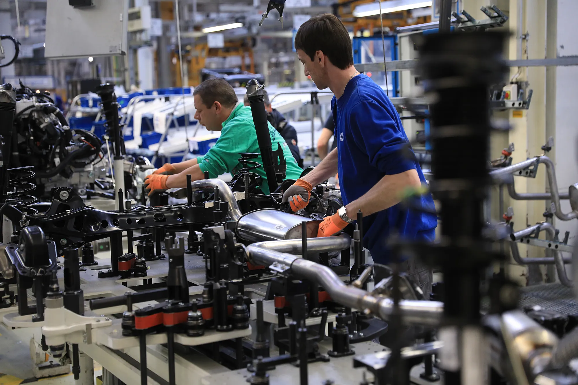 Employees attach the exhaust systems inside the VW factory in Emden, Germany.