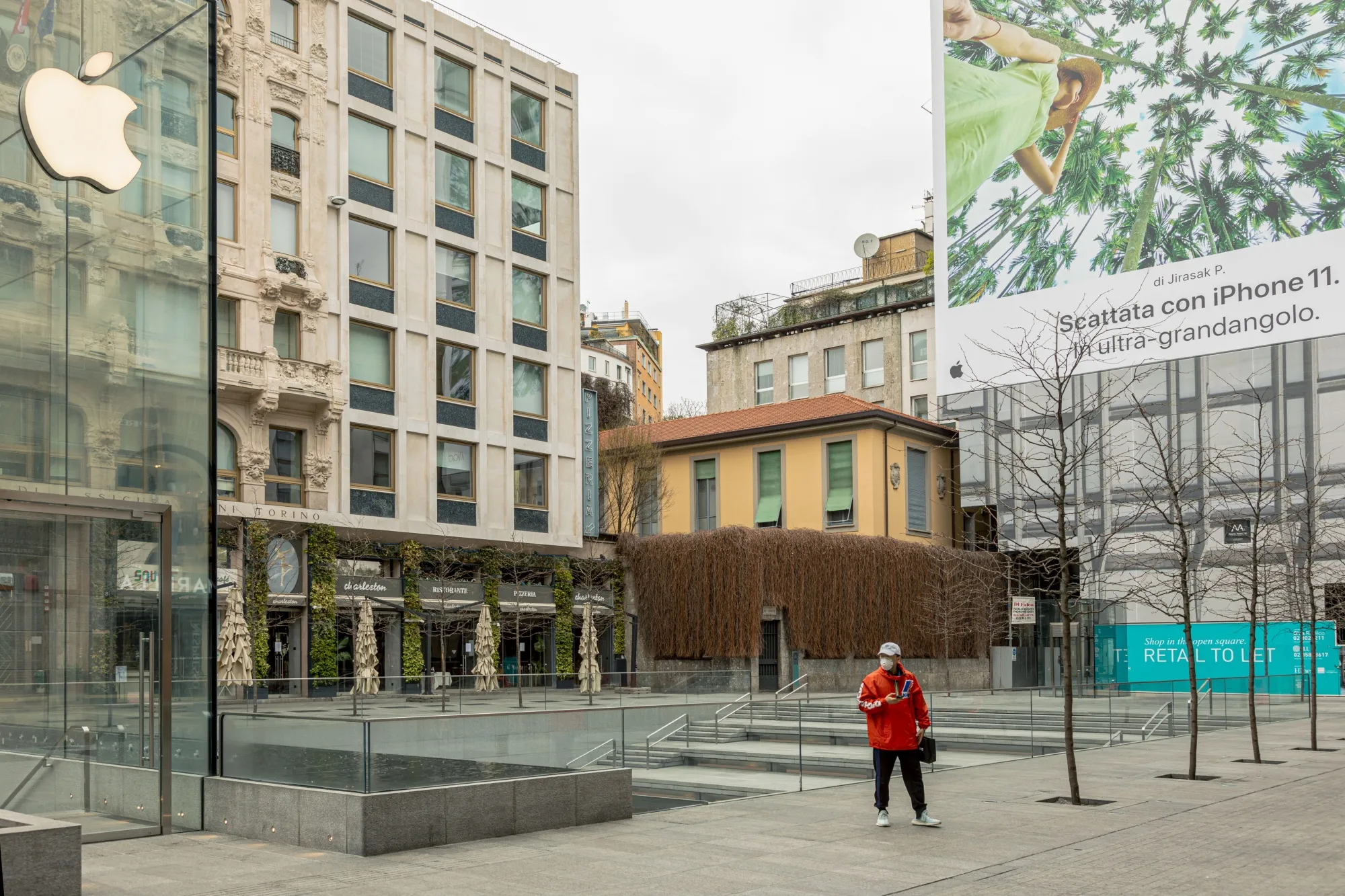 A pedestrian,&nbsp;wearing a protective face mask, stands near&nbsp;a closed Apple store in Milan on March 12.