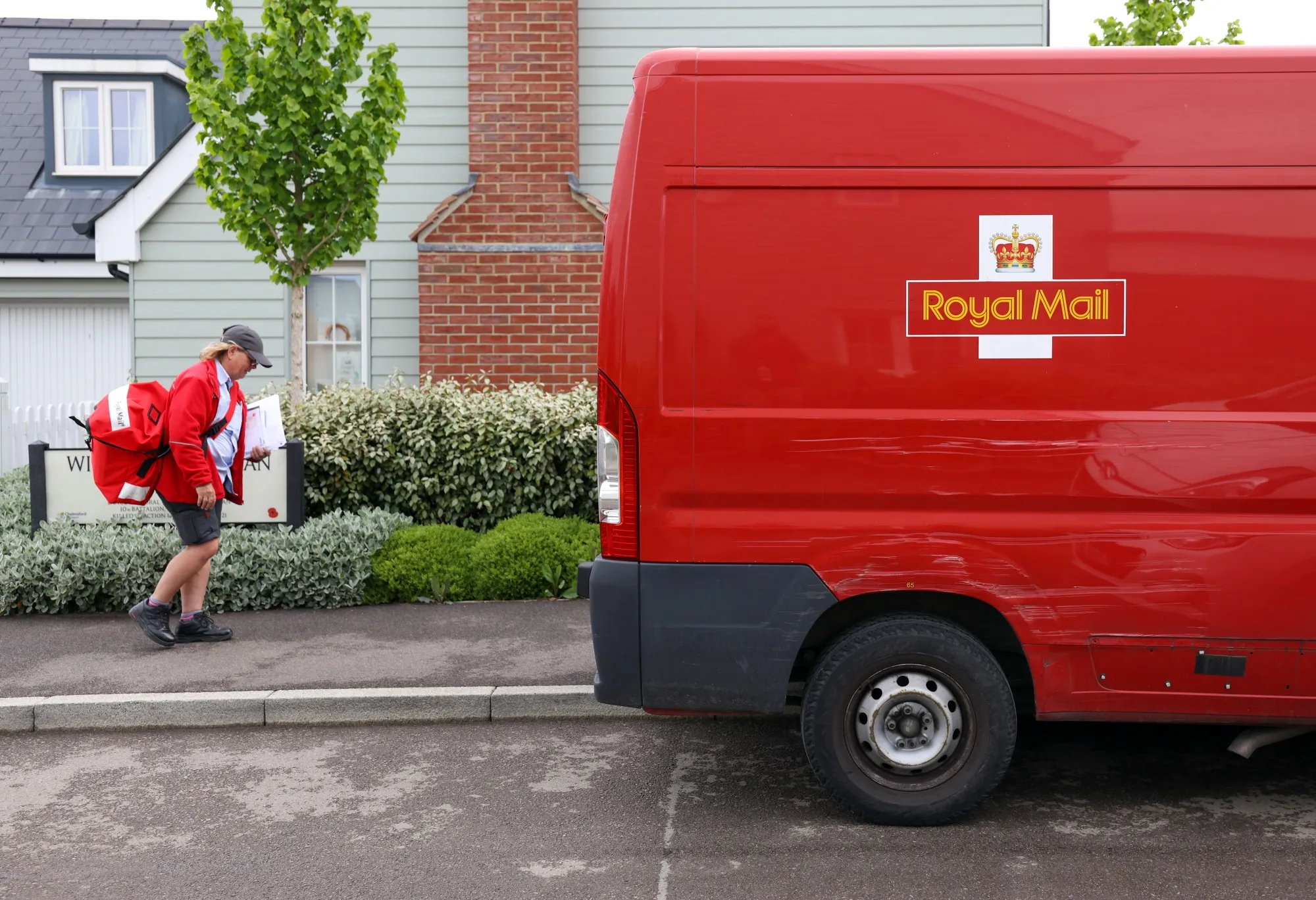 A postwoman for Royal Mail Plc carries post for delivery in Chelmsford, U.K.
