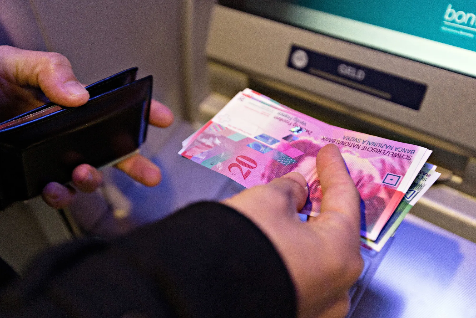 A customer collects Swiss franc banknotes from an automated teller machine in Zurich, Switzerland.