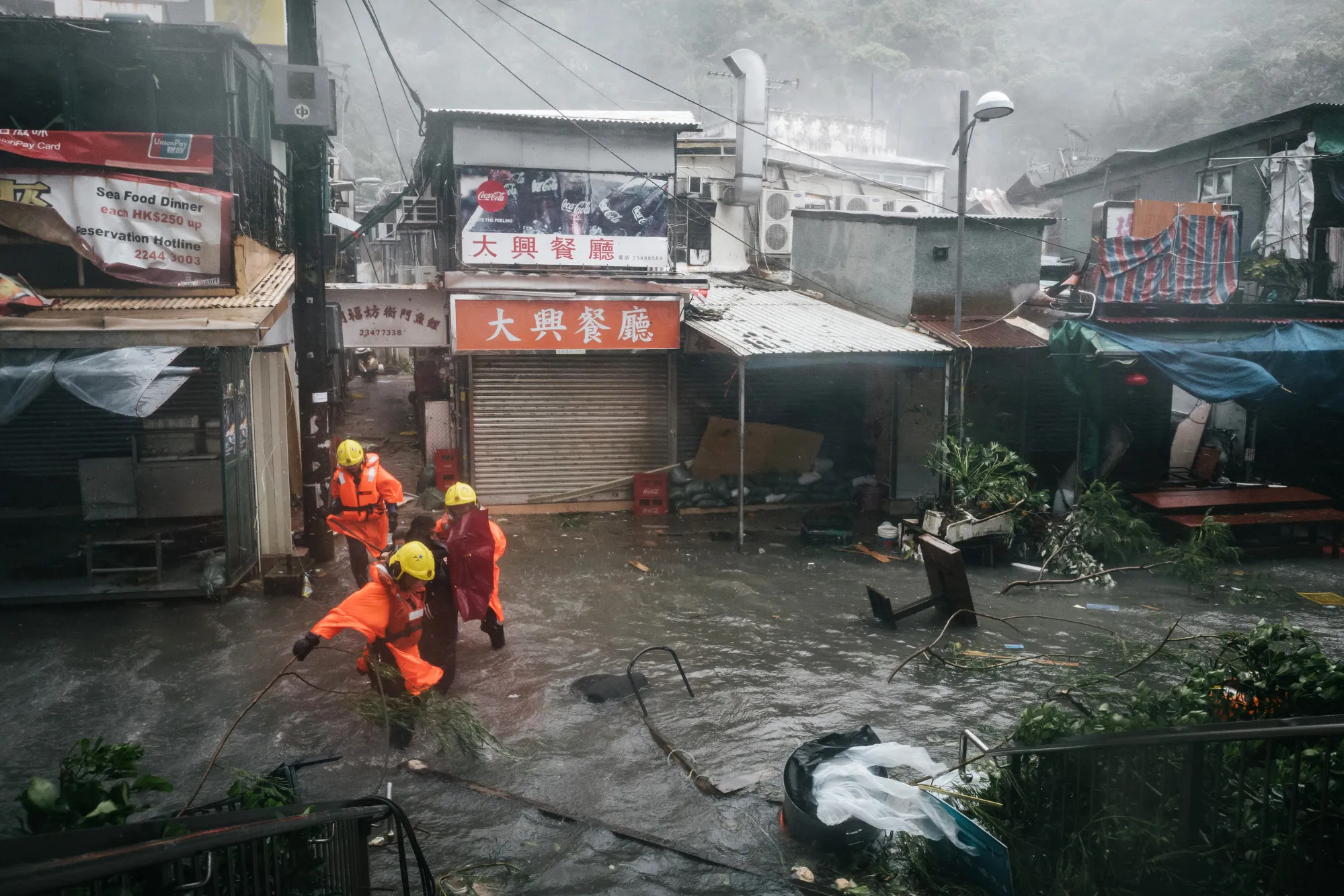 Firefighters escort people through floodwaters during a No. 10 Hurricane Signal in Hong Kong on Sept. 16.