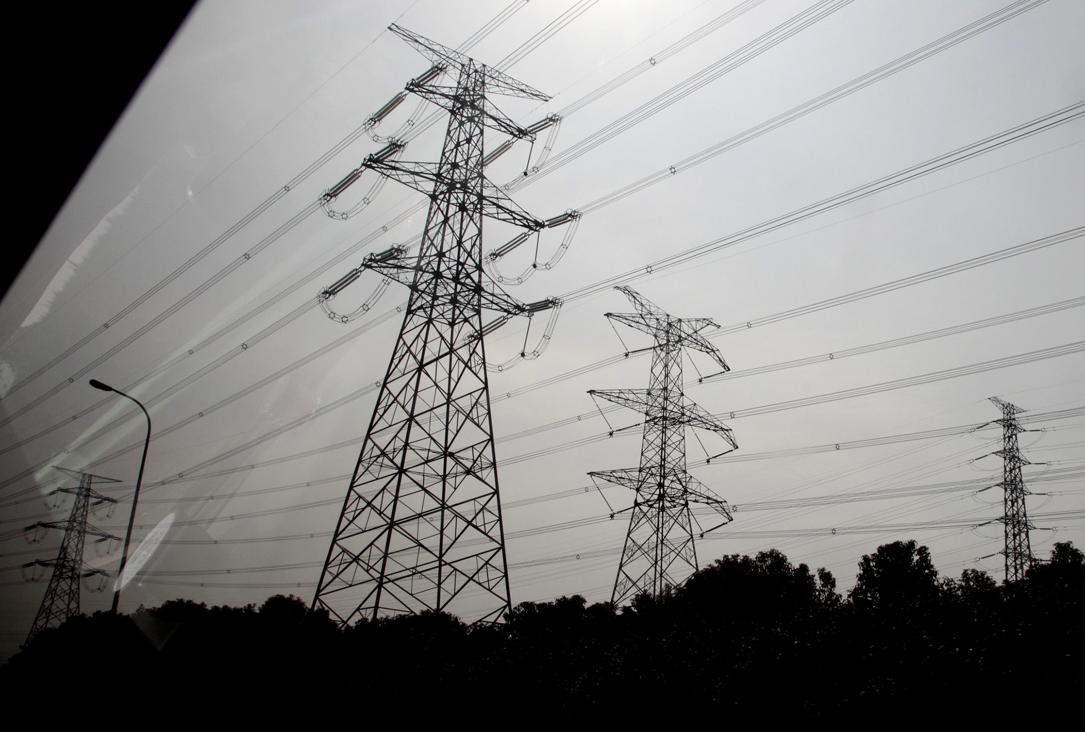 Electricity pylons are seen from a car window near the Yangshan Deep Water Port in Shanghai, China, on Thursday, Jan. 31, 2013. China's economic growth accelerated for the first time in two years as government efforts to revive demand drove a rebound in industrial output, retail sales and the housing market.
