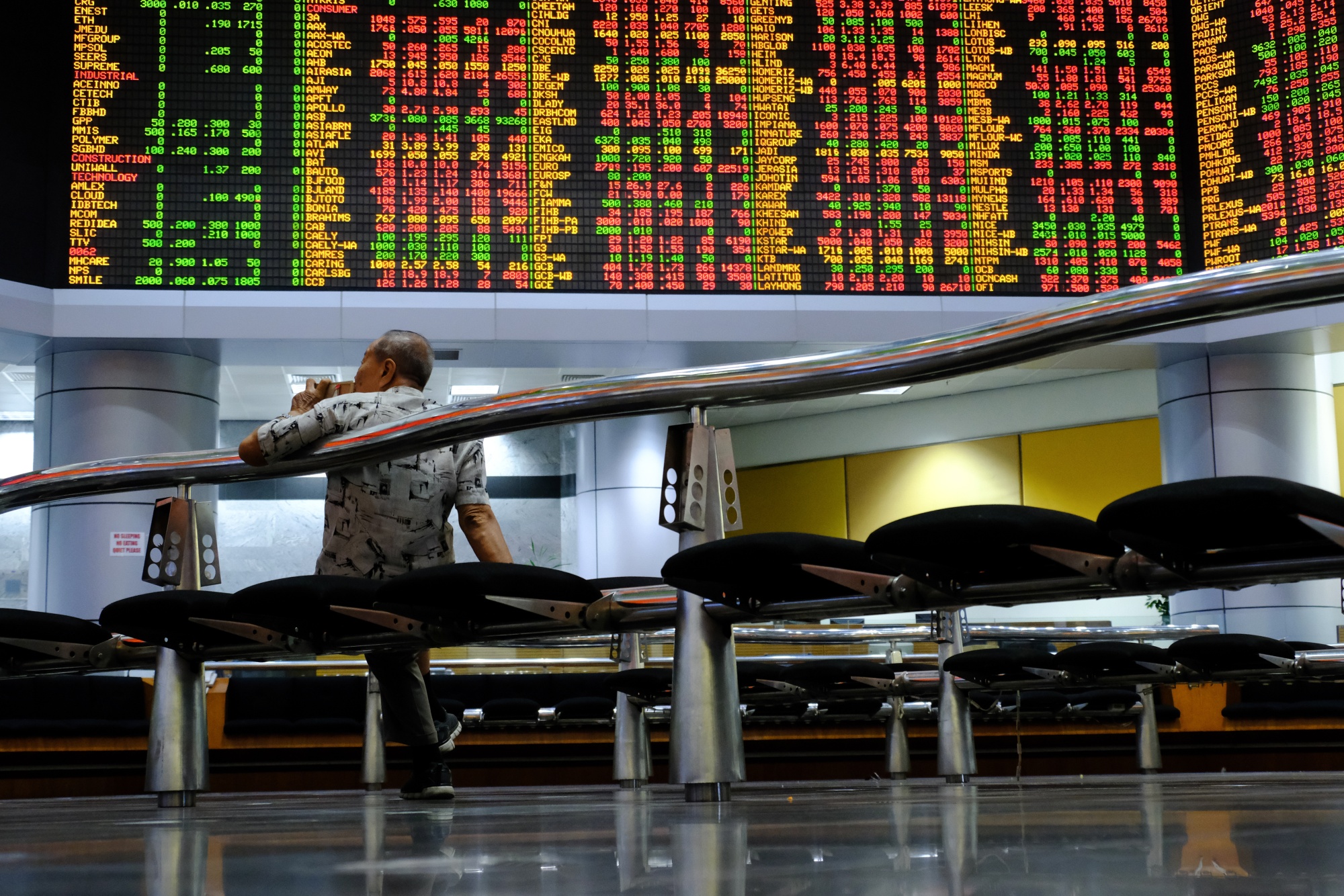 A man looks at stock prices displayed in the trading gallery of the RHB Investment Bank headquarters in Kuala Lumpur,&nbsp;Malaysia.