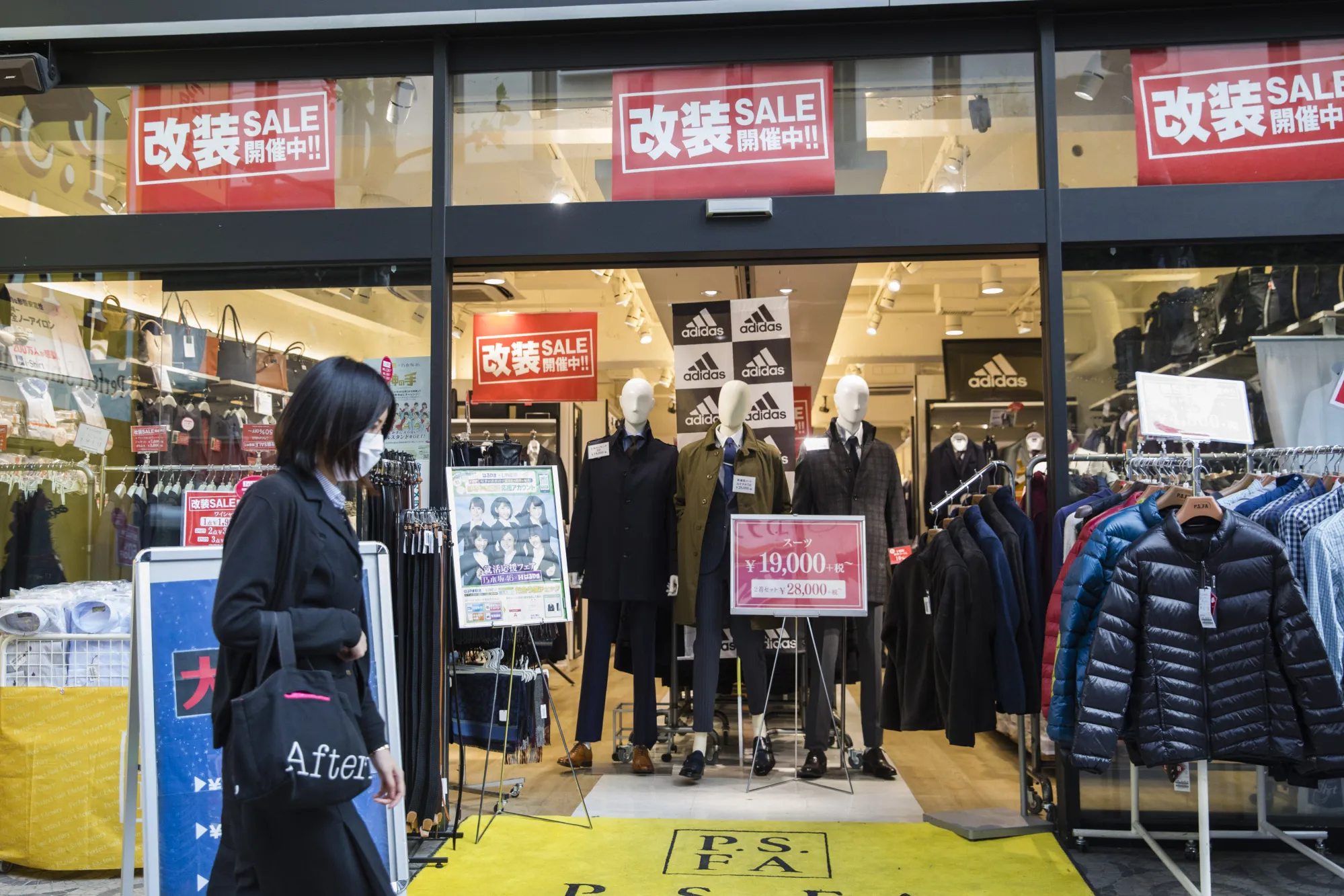 A pedestrian walks past a clothing store in the Shibuya district of Tokyo, Japan.