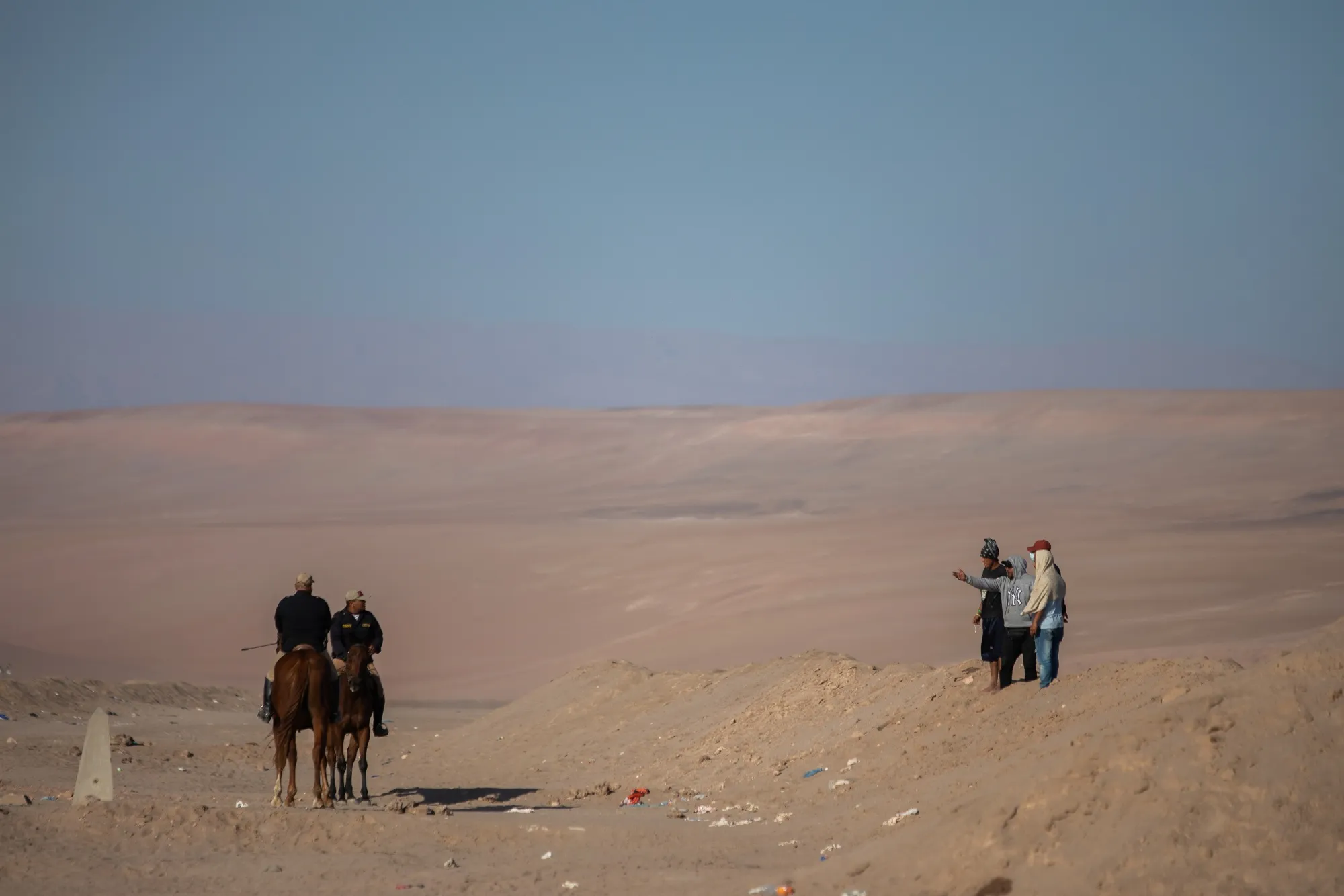 Police officers speak with migrants at the Peru-Chile border, in Tacna, Peru