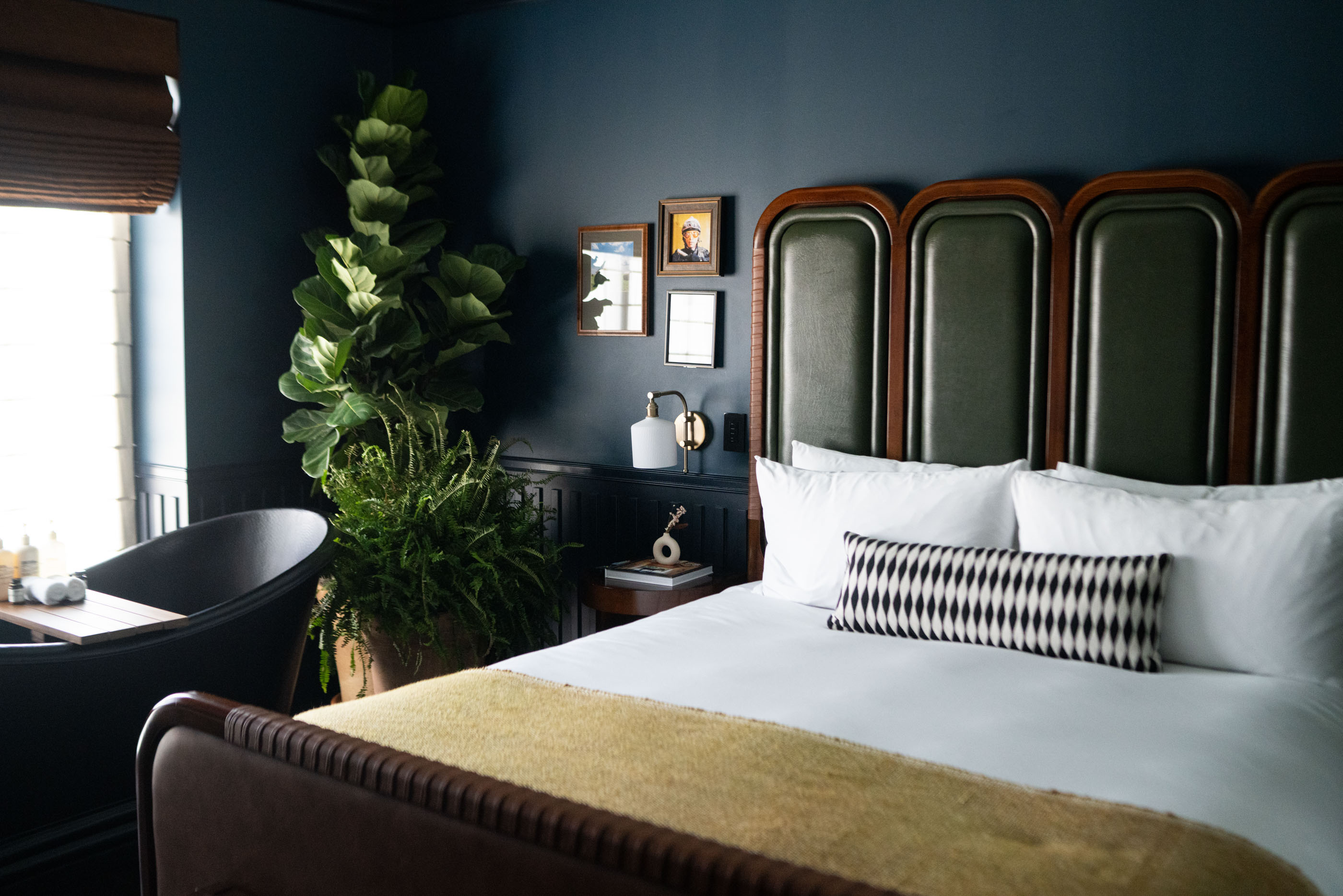 A crisp white bed in a navy blue-hued hotel room at the Manchester in Lexington.