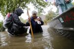 Andrew Mitchell helps his neighbor Beverly Johnson onto a rescue boat to escape the rising flood waters from Hurricane Harvey