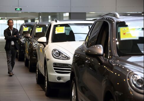 A customer walks past Porsche Cayennes at the Porsche Centre Shanghai Minhang showroom. Photographer: Tomohiro Ohsumi/Bloomberg