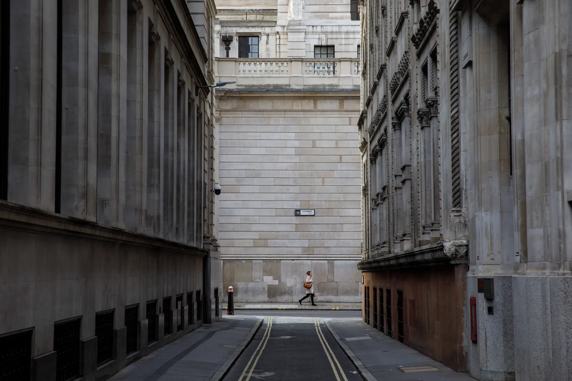 A pedestrian walks past the Bank of England in the City of London.