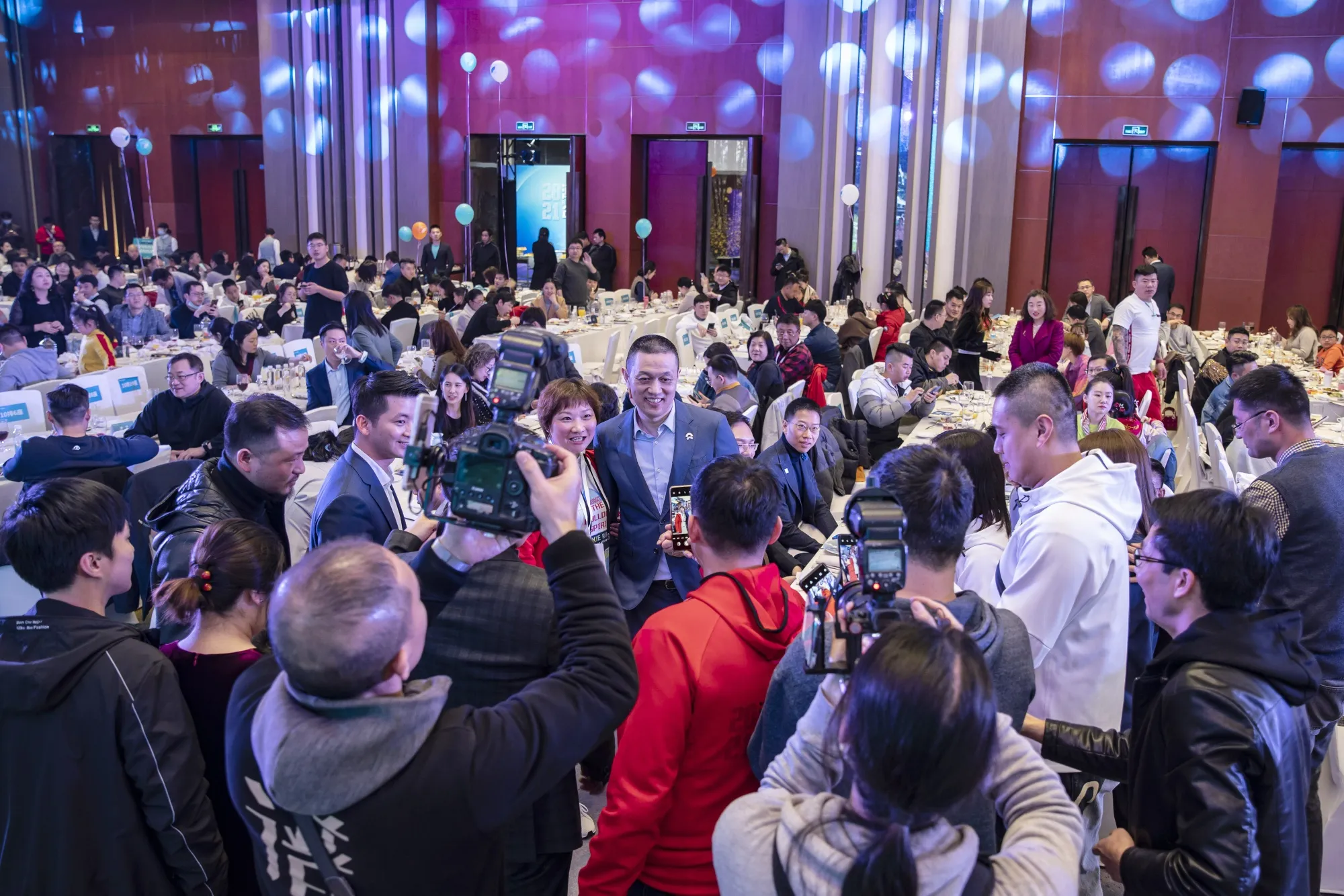 William Li, chief executive officer of Nio,&nbsp;center, poses for photographs with car owners during a gala dinner with customers in Shanghai in March.