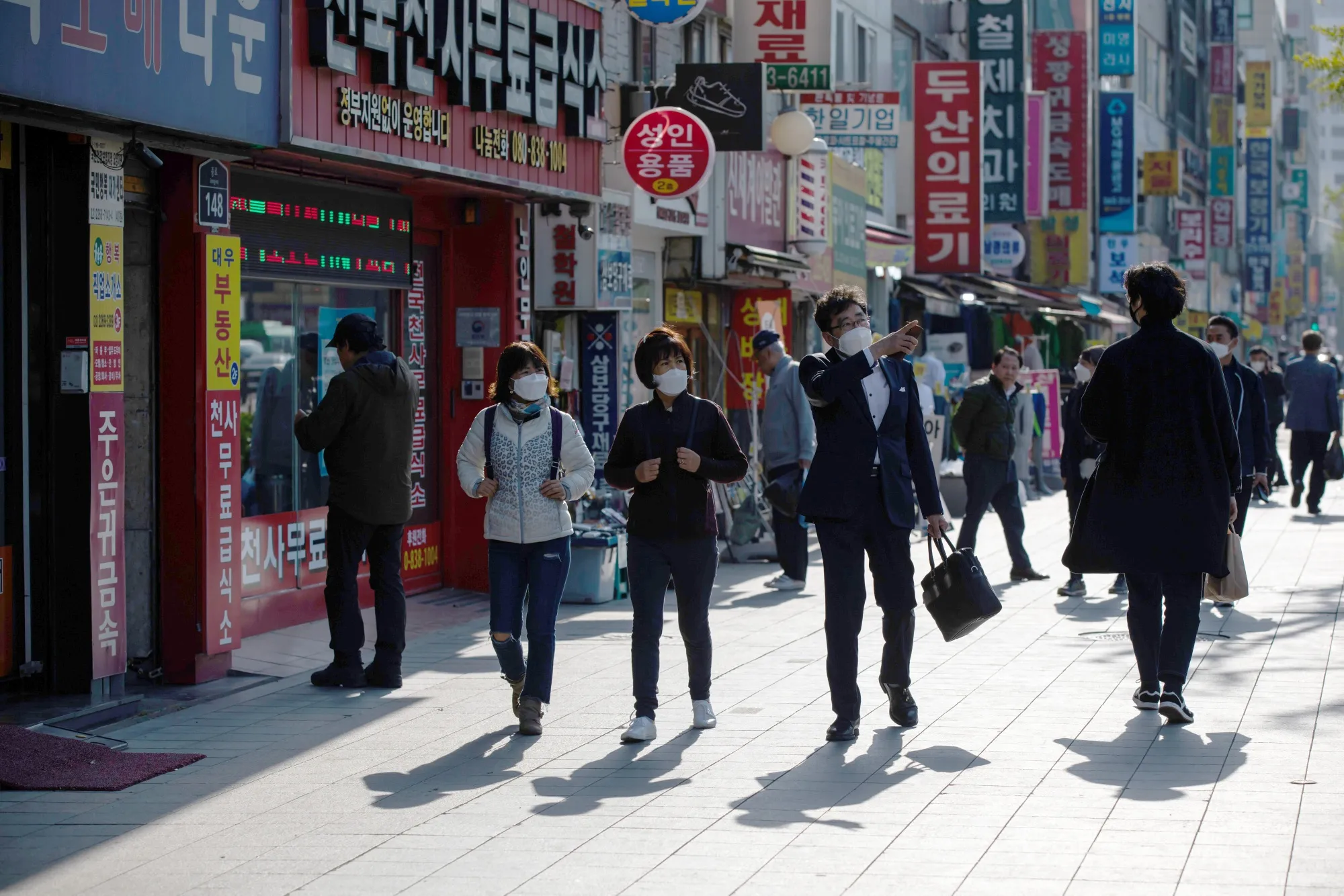 Pedestrians wearing protective masks walk past stores in the Jongno district of Seoul, South Korea, on&nbsp;April 24.