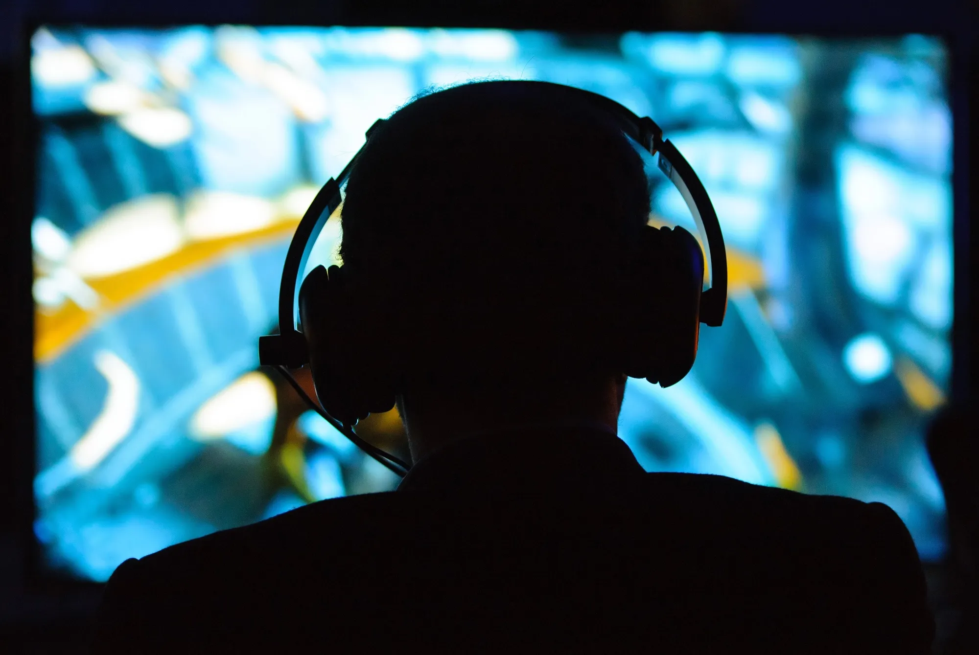 A man wearing headphones plays on a games console.