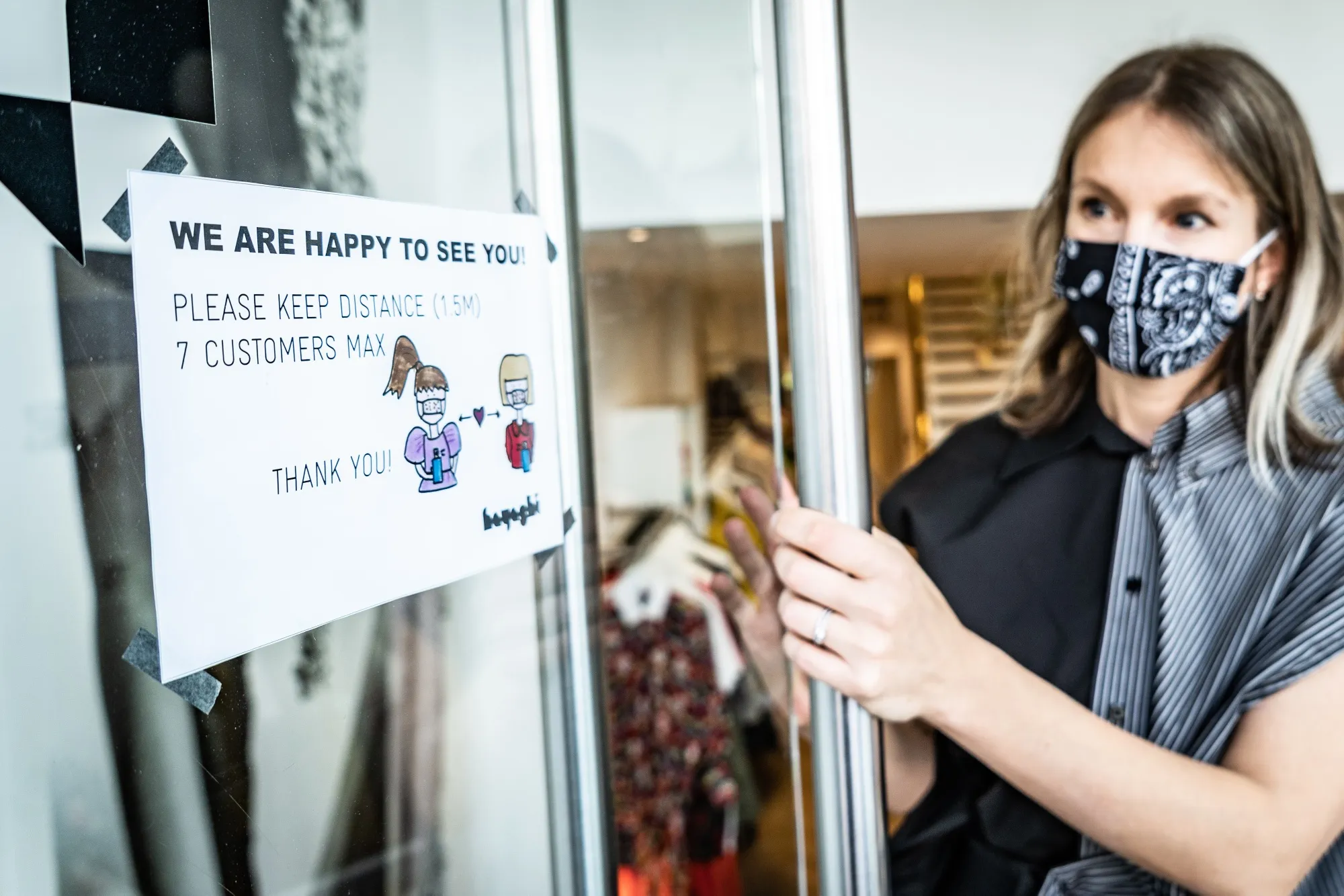 An employ opens the front door of a store in Frankfurt, Germany.