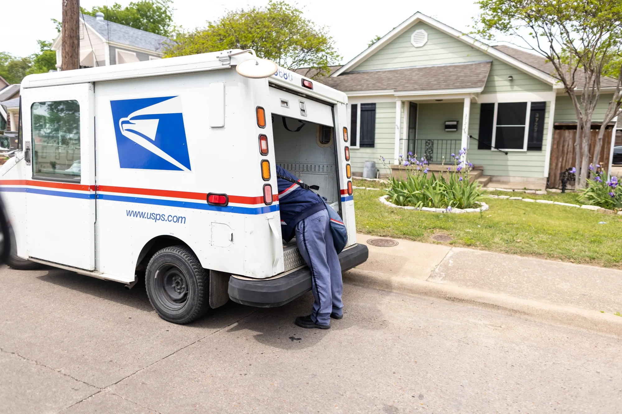 A United States Postal Service worker delivers mail from the back of a delivery truck&nbsp;in Dallas, Texas.