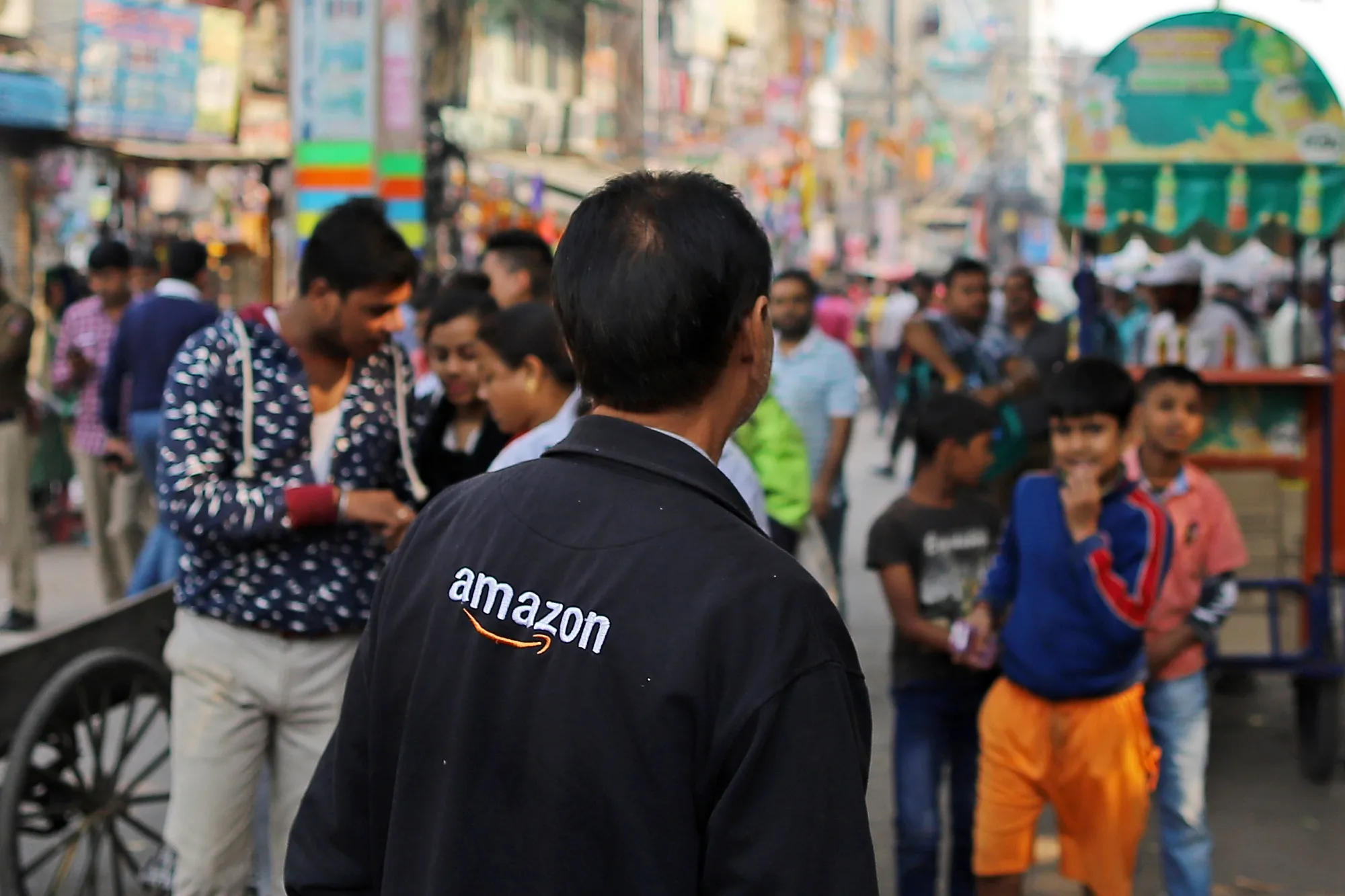 A vendor wears a jacket featuring the logo for Amazon.com Inc. at Sadar Bazaar in New Delhi.