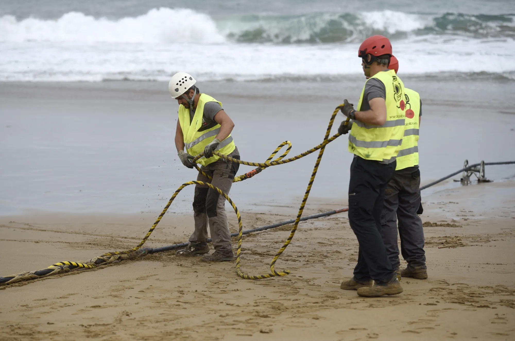 Operators handle an undersea fiber-optic cable at Arrietara beach in Spain.
