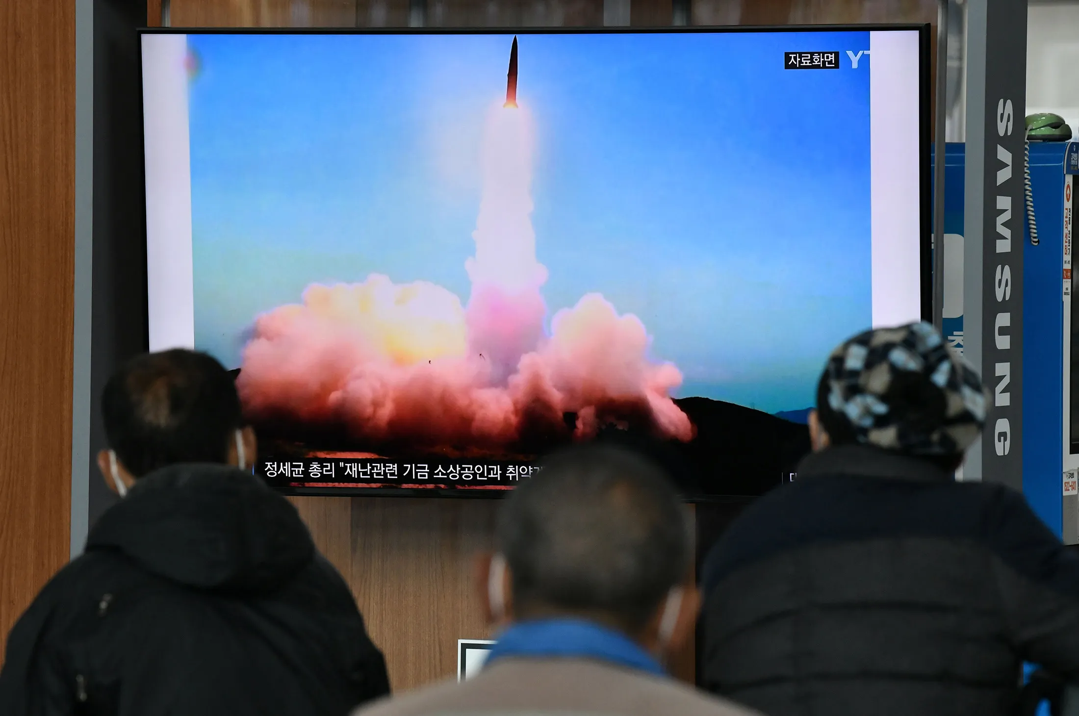 People watch a television news broadcast showing a file image of a North Korean missile test&nbsp;on March 21.