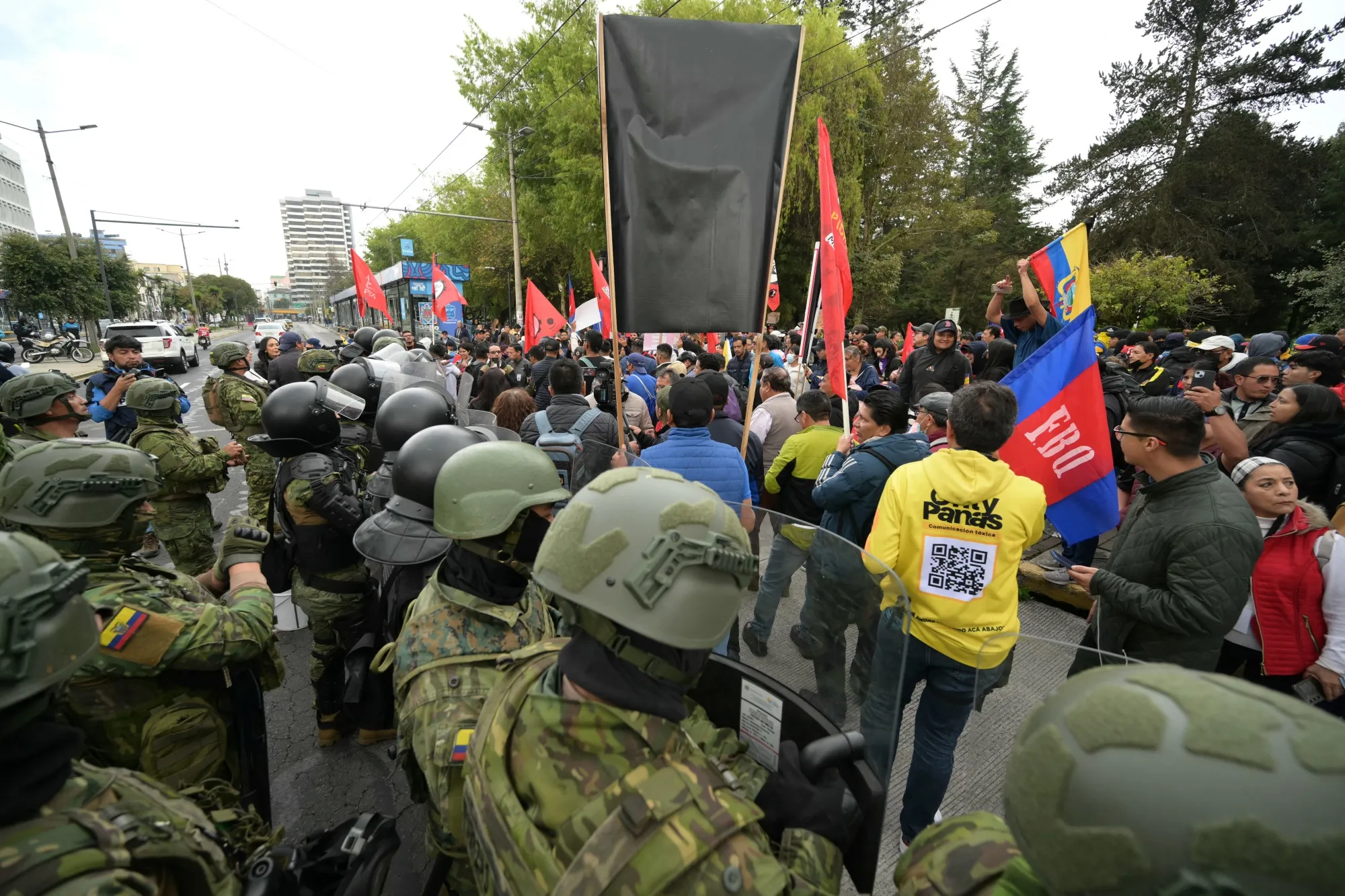 Manifestantes marchan frente a agentes de la policía antidisturbios mientras participan en una protesta en Quito el 15 de octubre.