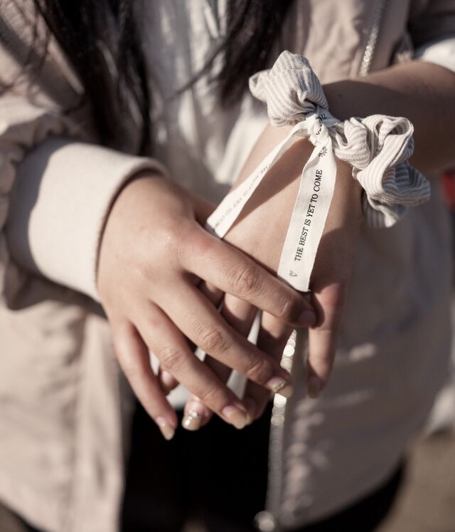 A closeup of the hands of Jia Jia, a 30-year old asylum seeker from China. JIa Jia is wearing a ribbon around her wrist that reads "The Best Is Yet To Come." 