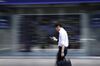 A pedestrian using his smartphone walks past an electronic stock board outside a securities firm in Tokyo, Japan.
