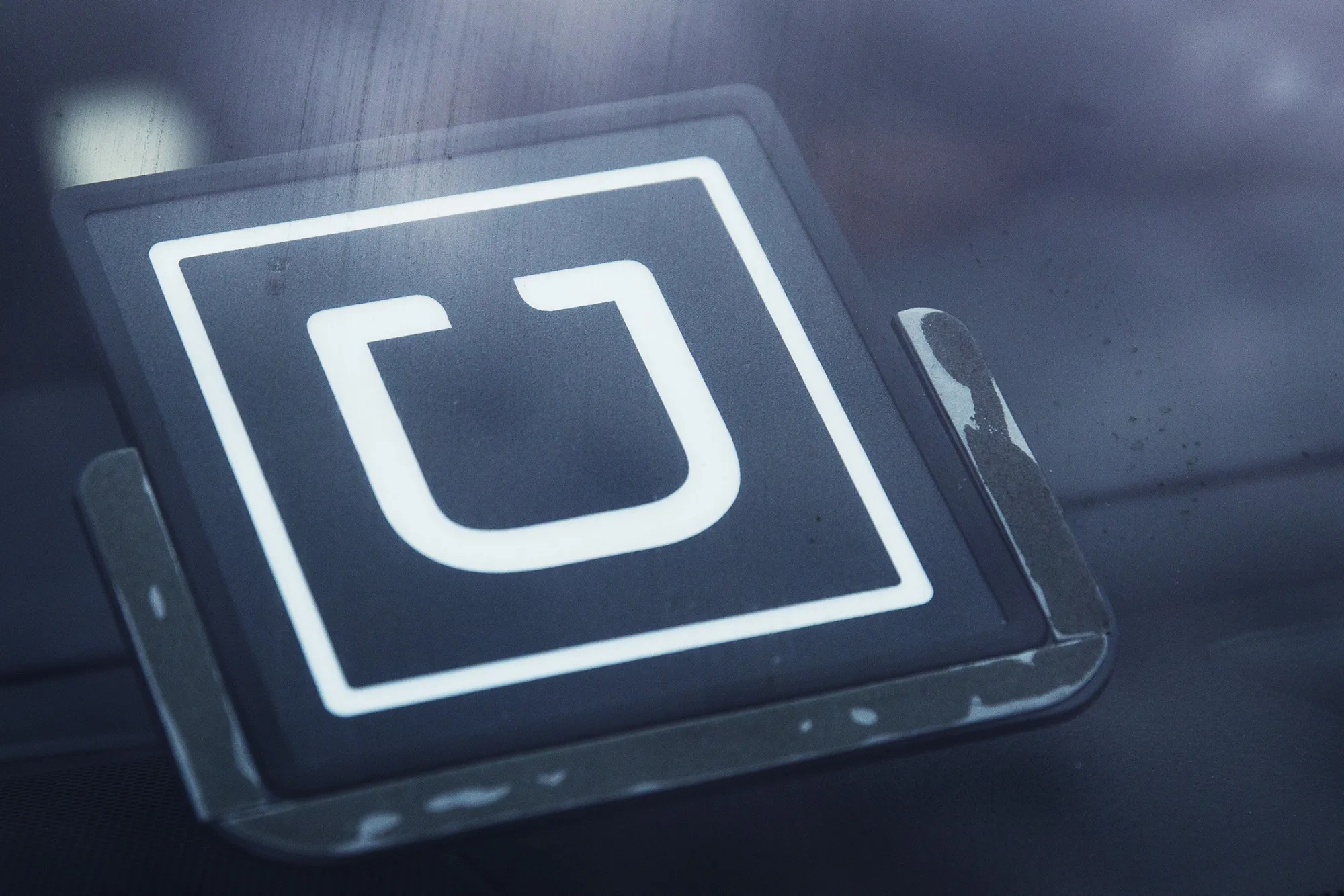 The Uber Technologies Inc. logo is displayed in the window of a car while Uber drivers protest against price cuts outside the company's offices in Long Island City, in the Queens borough of New York, U.S., on Monday, Feb. 1, 2016. Last week Uber Technologies Inc., the ride-hailing leader, reduced its uberX rates in New York City by 15 percent.

