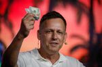 Peter Thiel holds hundred dollars bills as he speaks during the Bitcoin 2022 conference in Miami on April 7, 2022.