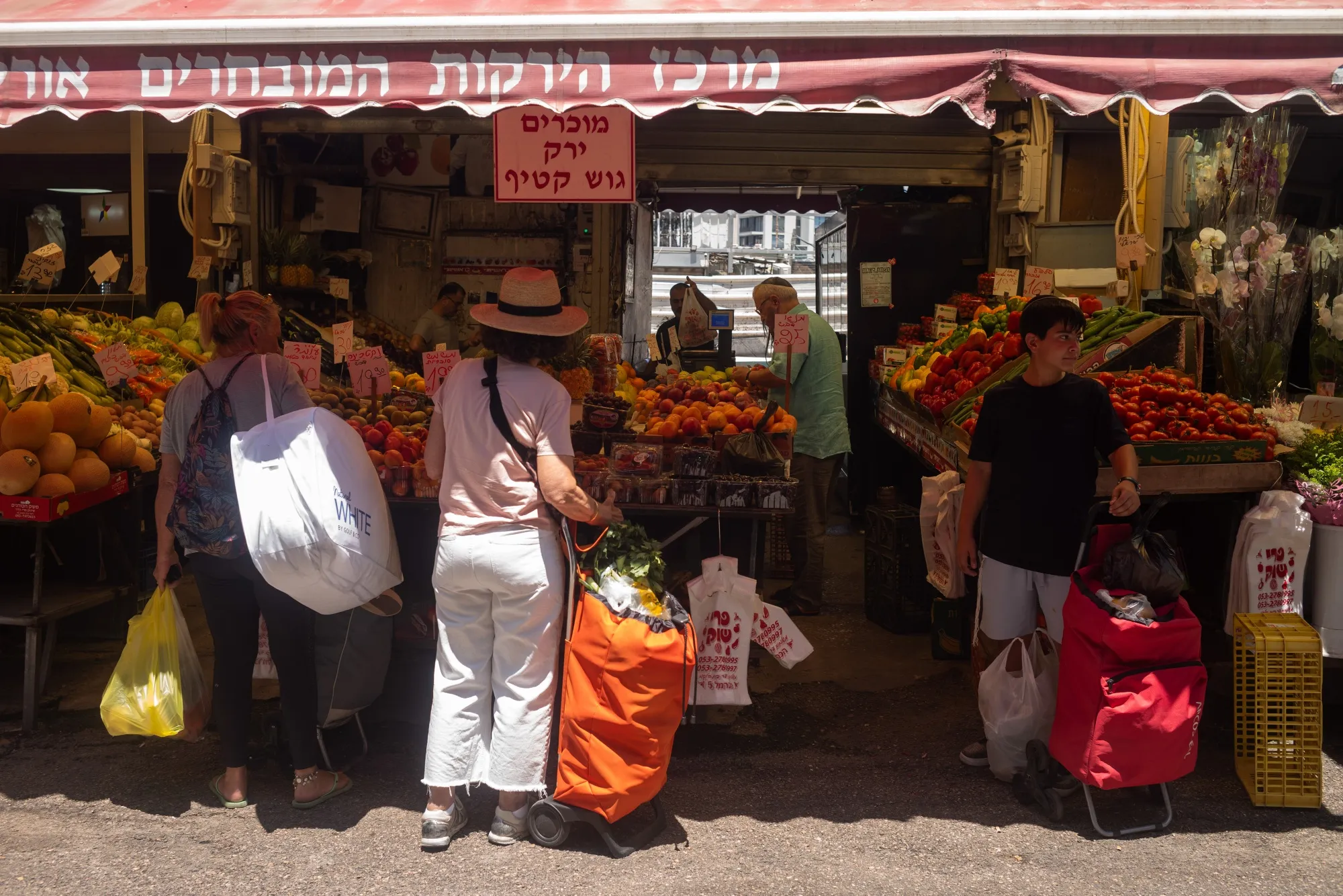 Shoppers at a fruit and vegetable stall at an outdoor market in Tel Aviv.