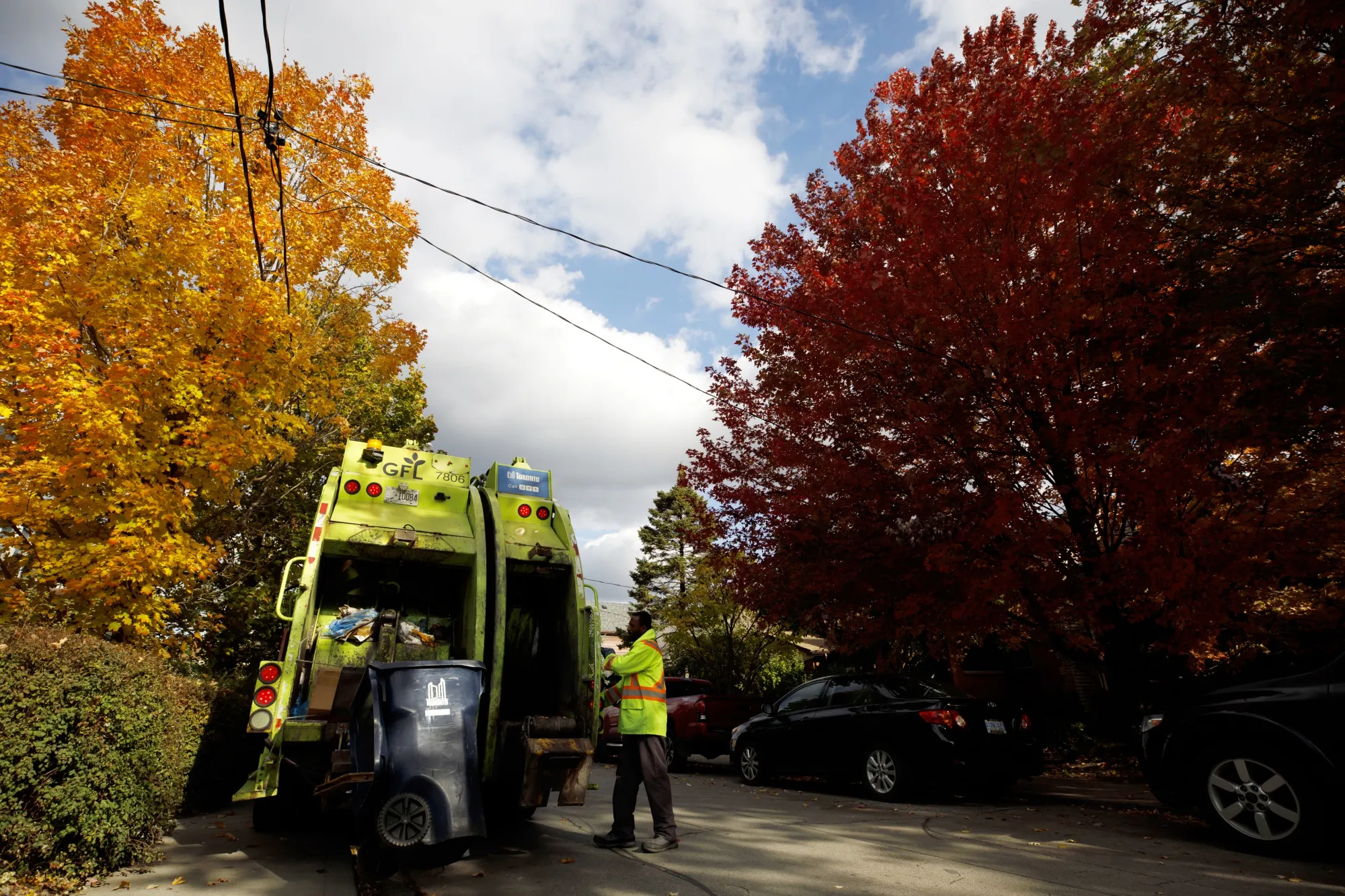 A worker loads household waste containers into a GFL Environmental Inc. garbage truck at a residential neighborhood in Toronto.