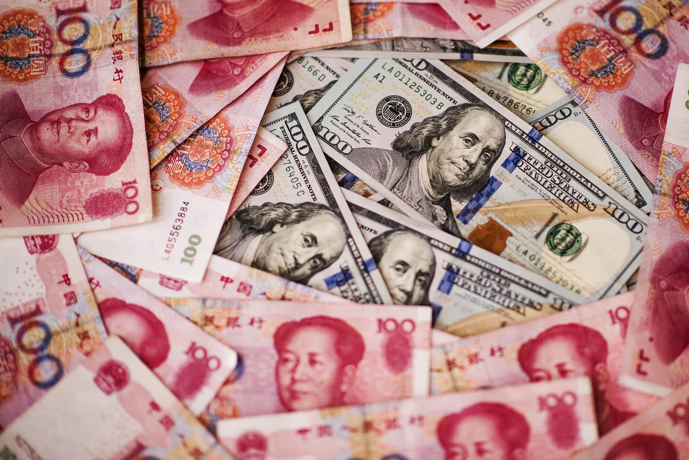 U.S. one-hundred dollar bills and Chinese one-hundred yuan banknotes are arranged for a photograph in Hong Kong, China, on Monday, July 20, 2015. The yuan has proven to be among the more resilient emerging-market currencies this year, having fallen less than 0.1 percent versus the dollar as China cut interest rates and the U.S. prepared to raise.
