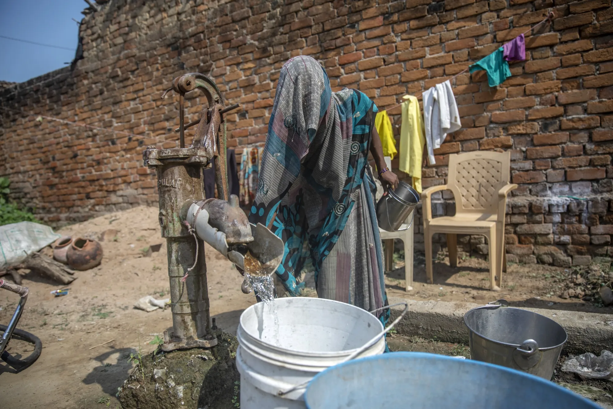 A woman collects water from a pump at a village in Banda District, Uttar Pradesh, India in 2020.