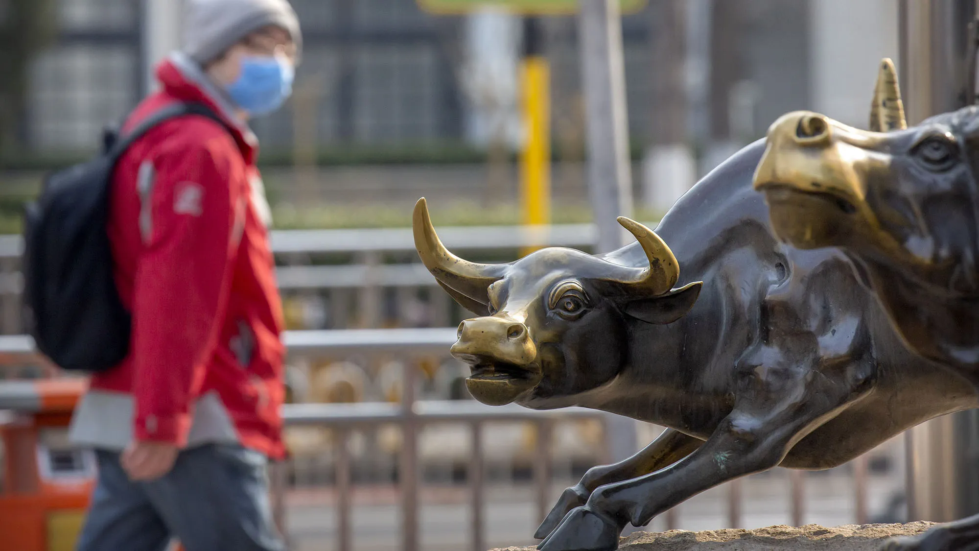 A man wearing a face mask walks past statues of bulls in Beijing on&nbsp;Feb. 28.
