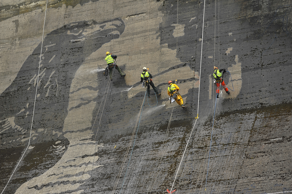 Workers suspended on cables to &quot;paint&quot; the walls of Poland's Solina Dam.