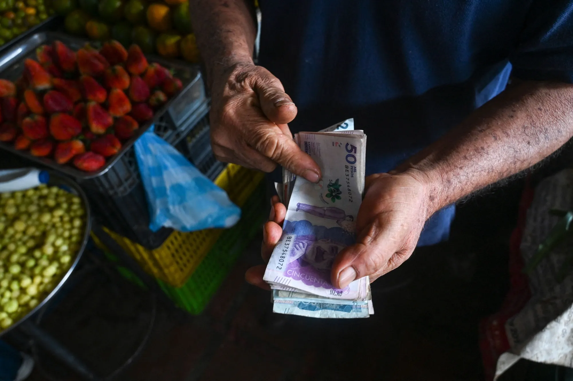 A vendor counts Colombian pesos.