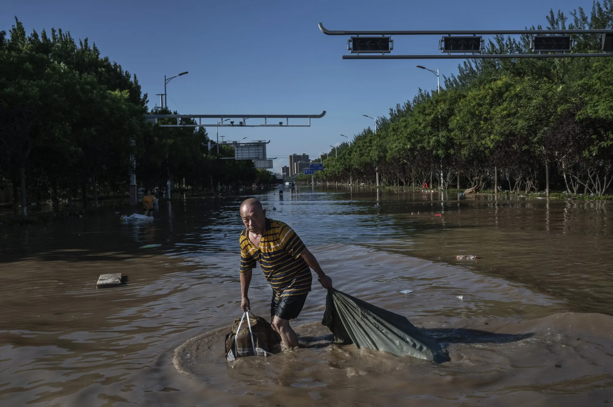 A man wades through receding floodwaters in Zhuozhou, Hebei Province on Aug. 5.