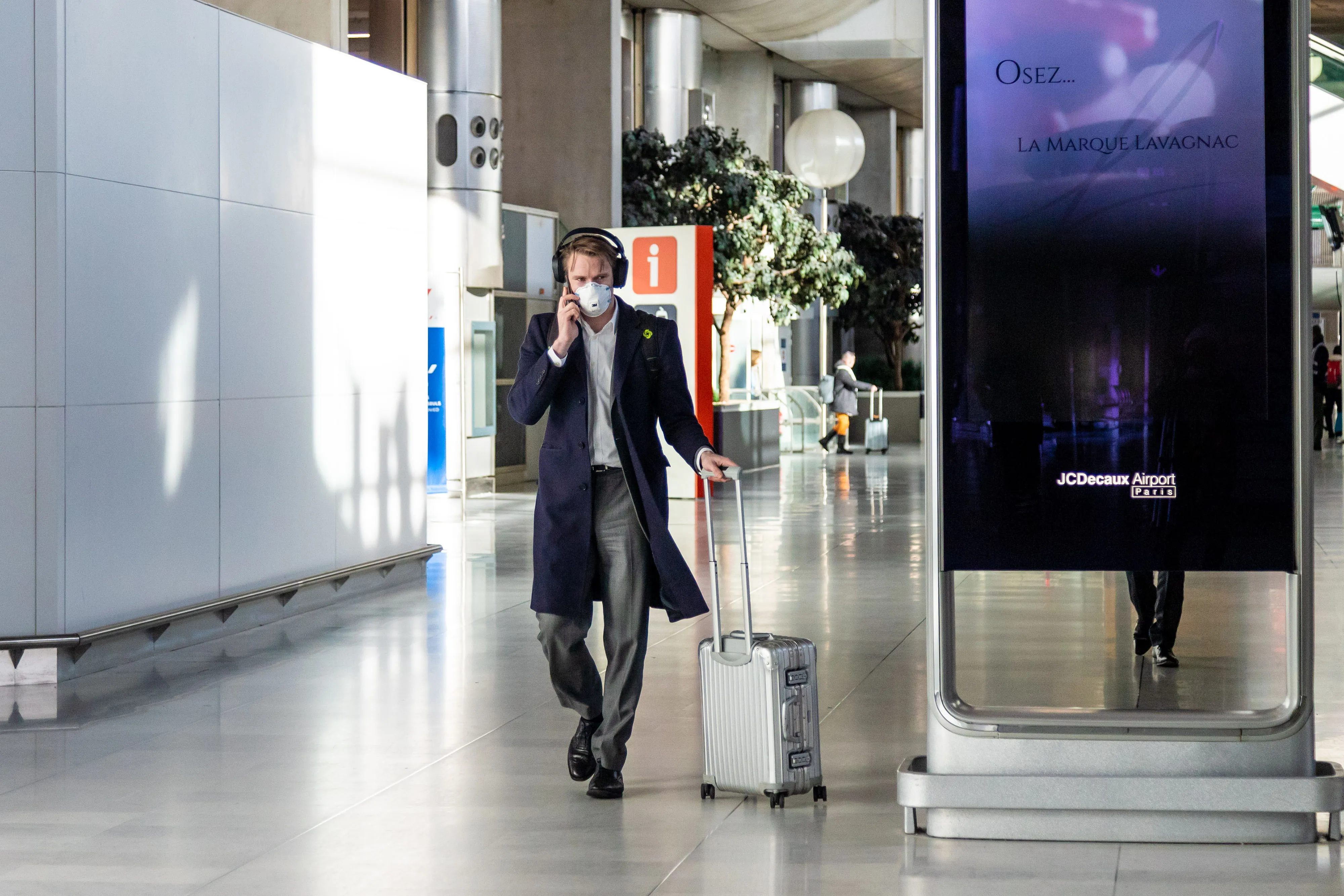 A passenger in a protective face mask wheels luggage at Charles de Gaulle airport.