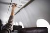 Woman reaching for air vent in airplane